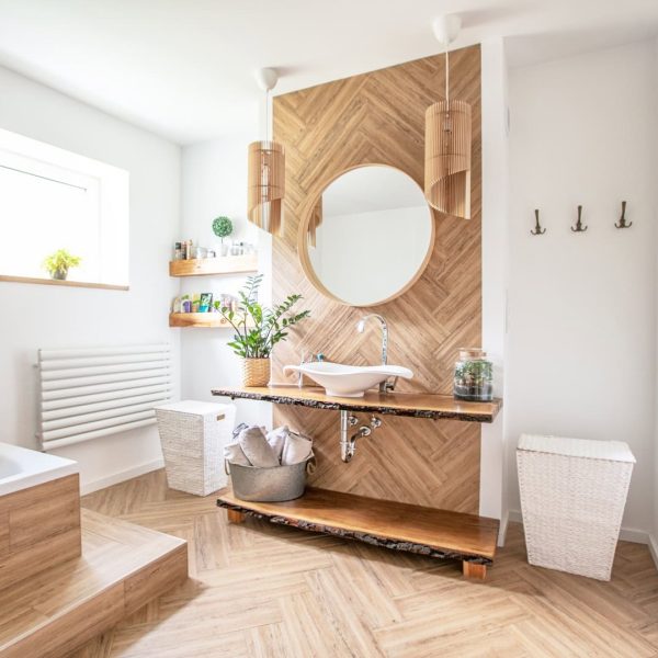 White sink on wood counter with a round mirror hanging above it. Bathroom interior.